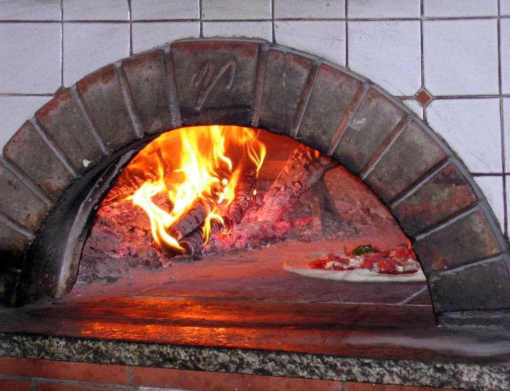 La bocca del forno a legna con la fiamma viva