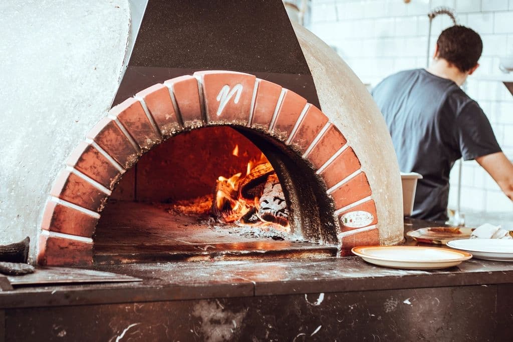 Il pizzaiolo davanti al forno a legna acceso