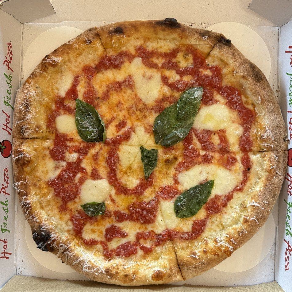Margherita intera con basilico, appena sfornata nel cartone